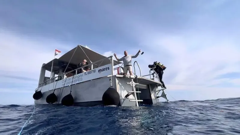 Bateau de plongée avec des personnes à bord et un plongeur équipé