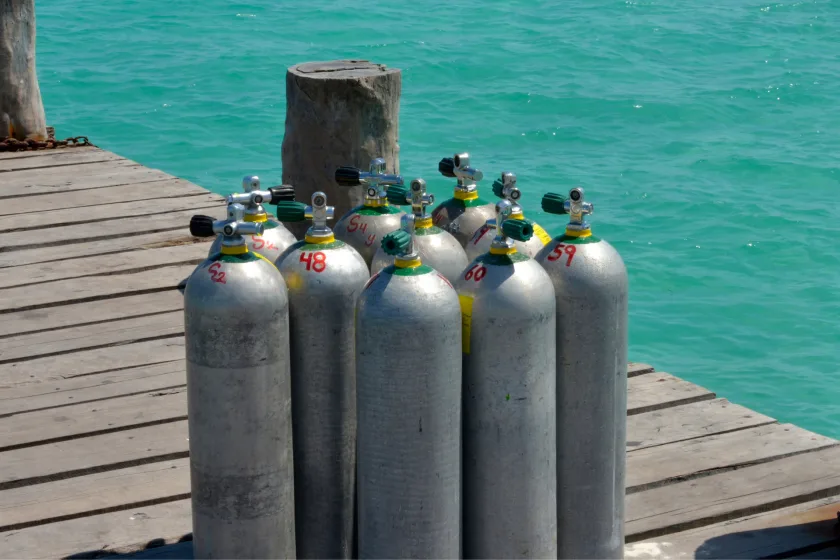 Bouteilles de plongée alignées sur un ponton en bois au soleil