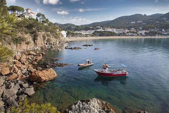 Crique rocheuse avec deux bateaux amarrés dans une eau turquoise claire
