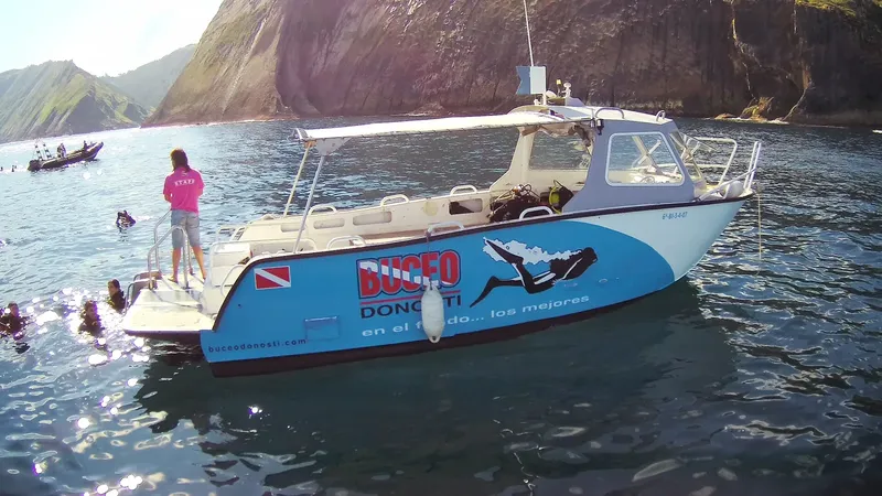 Bateau de plongée bleu et blanc avec des plongeurs préparant une sortie