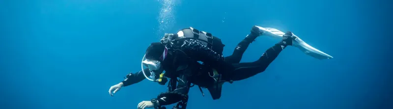 Deux plongeurs en combinaison explorent les profondeurs bleues de l'océan