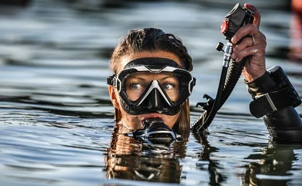Plongeuse avec masque et détendeur, visage partiellement immergé dans l'eau