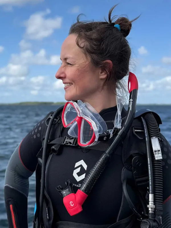 Plongeuse souriante avec masque et détendeur dans l'eau bleue