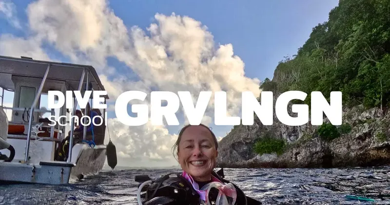 Plongeuse souriante avec son équipement devant un bateau et le ciel