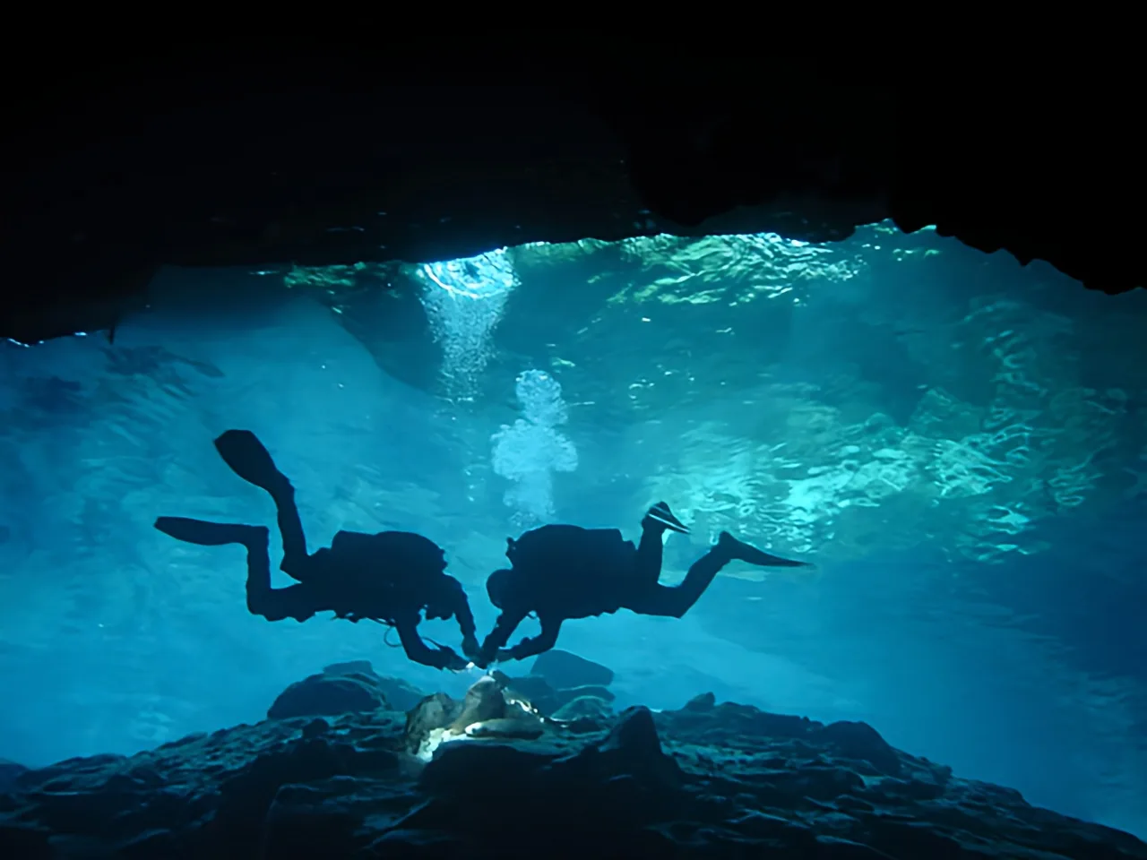 Deux plongeurs explorent une grotte sous-marine éclairée