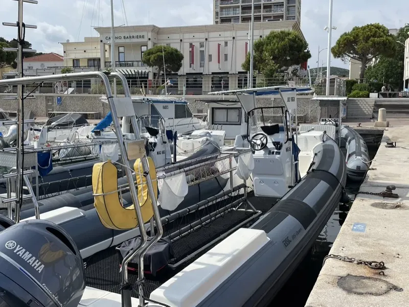 Plusieurs bateaux semi-rigides amarrés sur un quai ensoleillé près d'immeubles