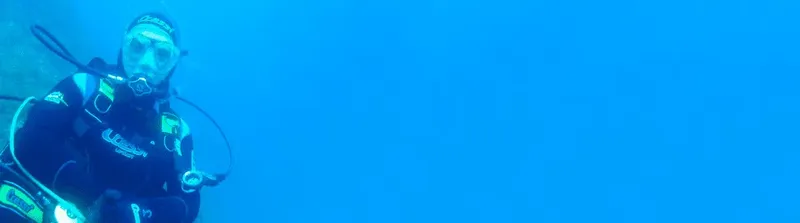 Plongeur en combinaison noire nageant dans une eau bleue claire