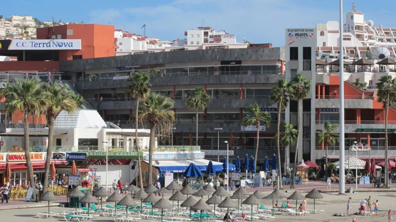 Vue d'une plage avec des bâtiments, des palmiers et des parasols