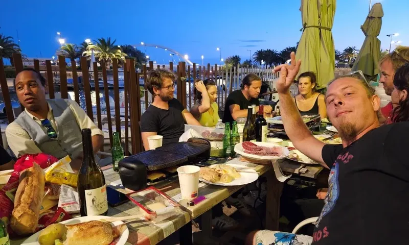 Groupe de personnes souriantes autour d'une table avec nourriture et boissons