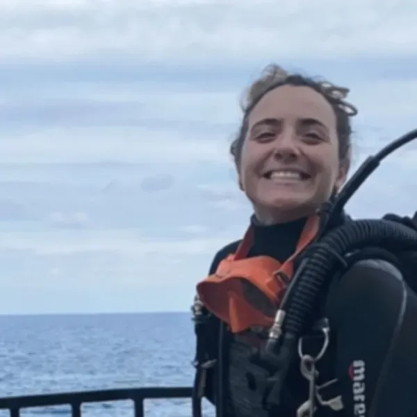 Plongeuse souriante avec son équipement complet, prête pour une immersion