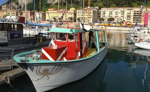 Bateau de plongée amarré dans un port avec des personnes à bord