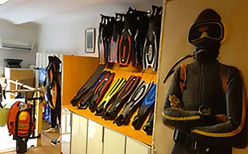 Intérieur d'un centre de plongée avec palmes, bouteilles et mannequin