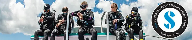 Plongeurs équipés assis sur le bord d'un bateau avec un logo