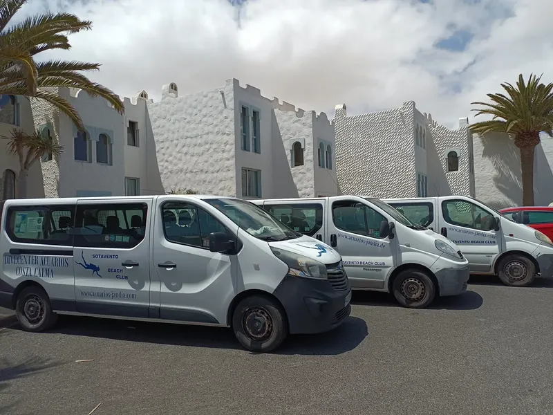Vue de plusieurs fourgonnettes blanches avec logos devant un bâtiment blanc