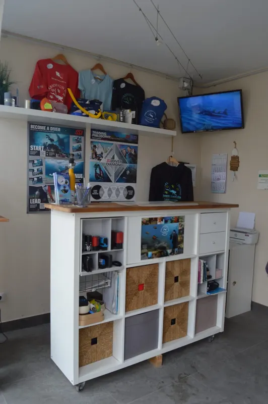 Comptoir d'accueil d'un centre de plongée avec affiches et équipements