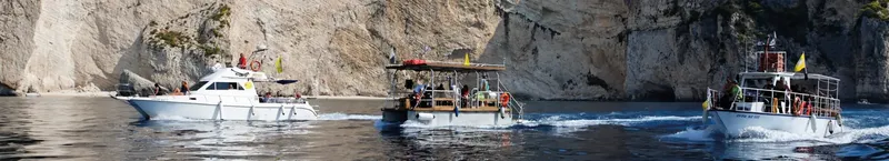 Trois bateaux de plaisance naviguent sur une mer calme ensoleillée