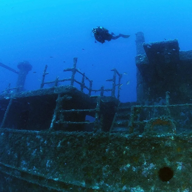 Plongeur explorant l'épave d'un navire sous l'eau bleu profond