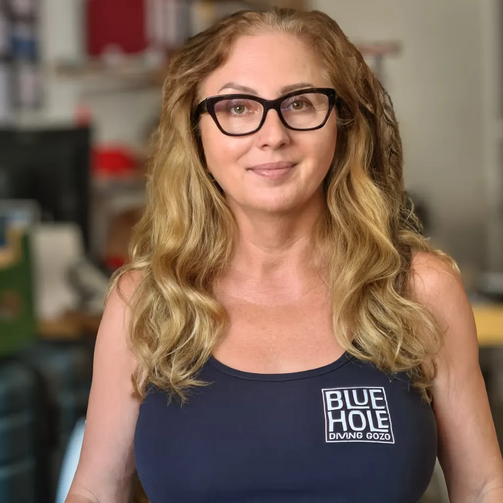 Femme souriante portant des lunettes et un débardeur bleu foncé