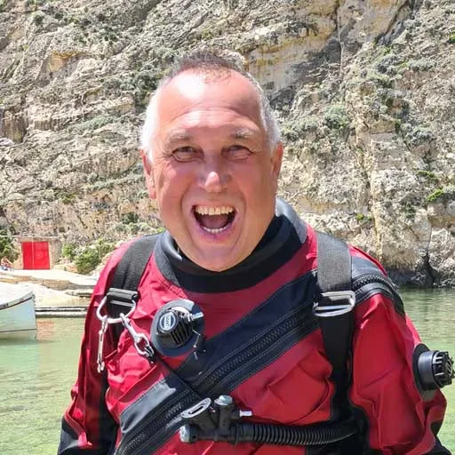 Plongeur souriant portant une combinaison et un gilet stabilisateur rouge