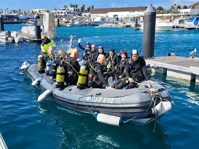 Groupe de plongeurs en combinaison sur un bateau semi-rigide dans un port
