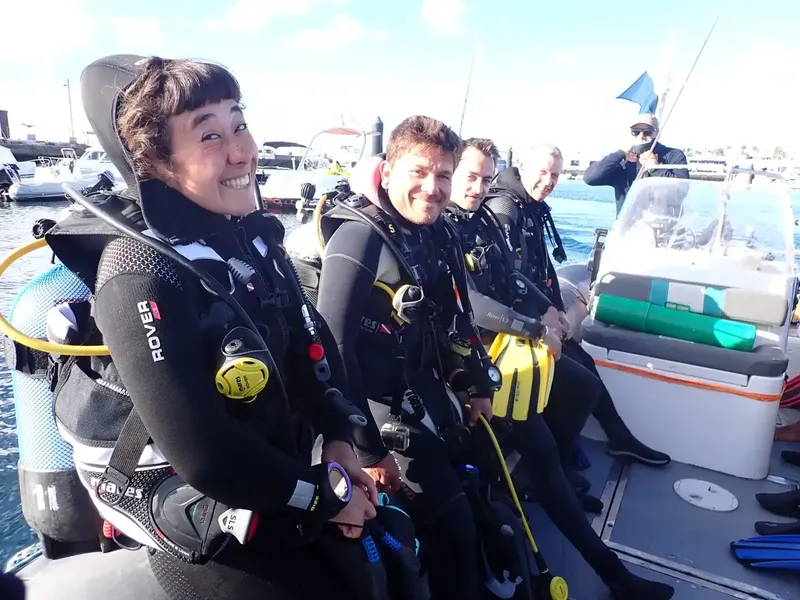 Plongeurs souriants sur un bateau pneumatique en direction d'un site