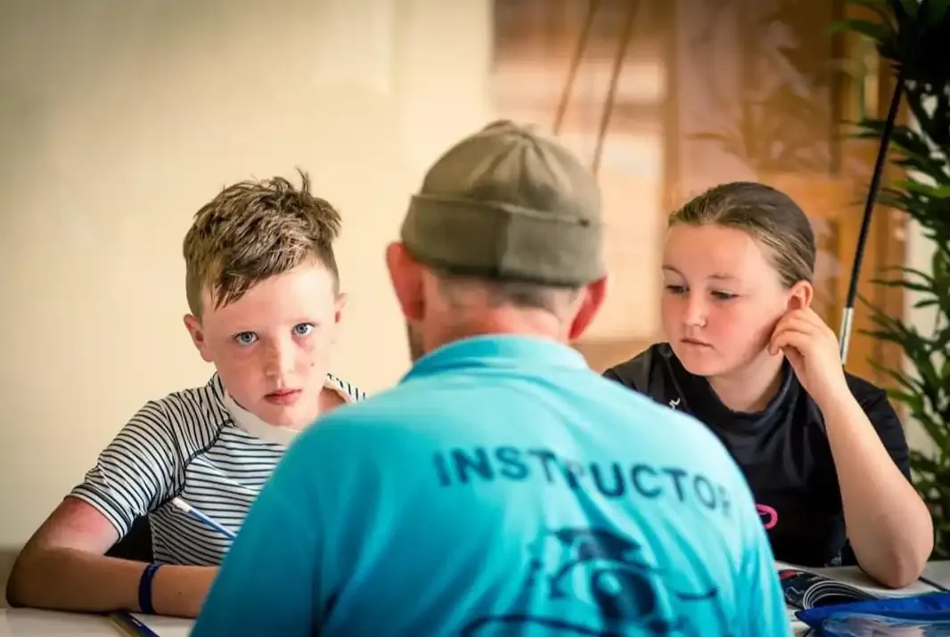 Trois personnes assises autour d'une table, un instructeur explique