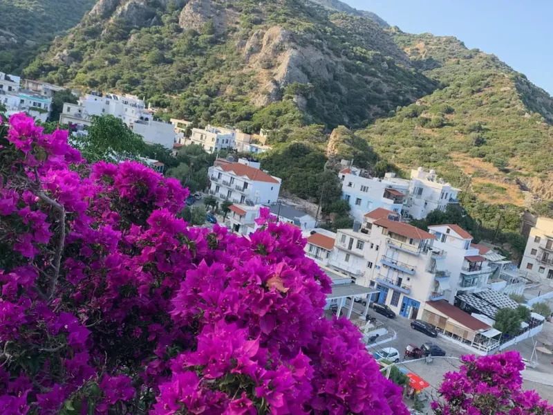 Village blanc avec des bougainvilliers roses au premier plan et montagne