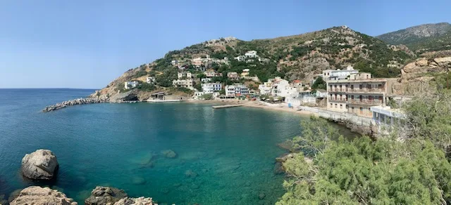 Vue d'une crique avec des bâtiments, une plage et la mer turquoise
