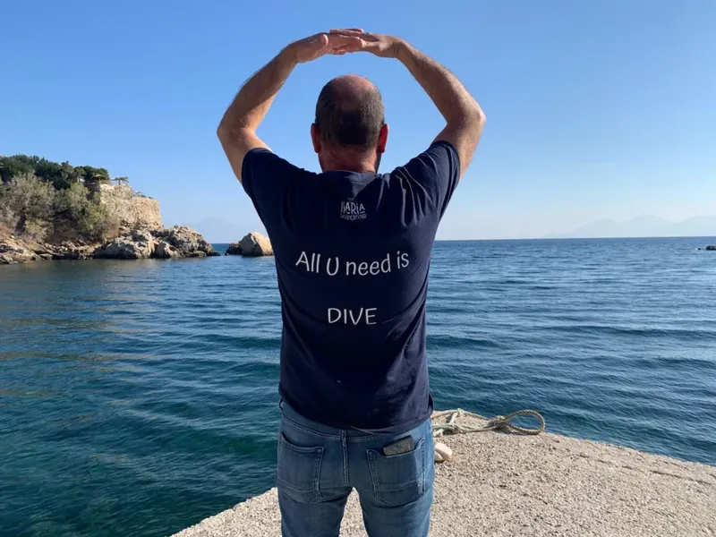 Homme regardant la mer avec un t-shirt portant un message sur la plongée