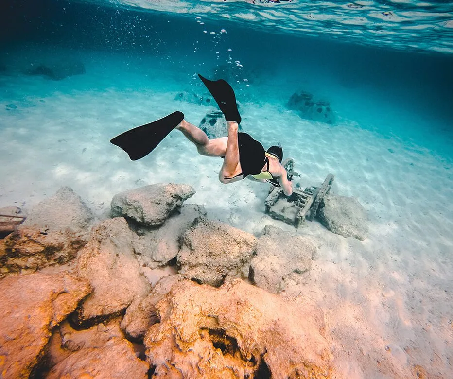 Plongeuse explorant un récif corallien avec des rochers et du sable