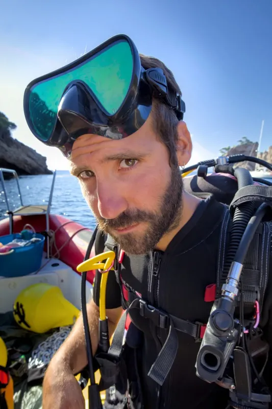 Plongeur avec masque et équipement, regardant vers l'objectif, bateau en arrière-plan