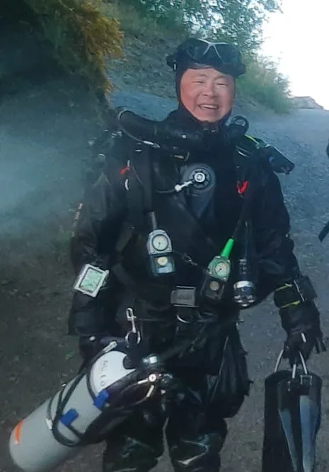 Plongeur souriant équipé de son matériel complet sur un terrain vague