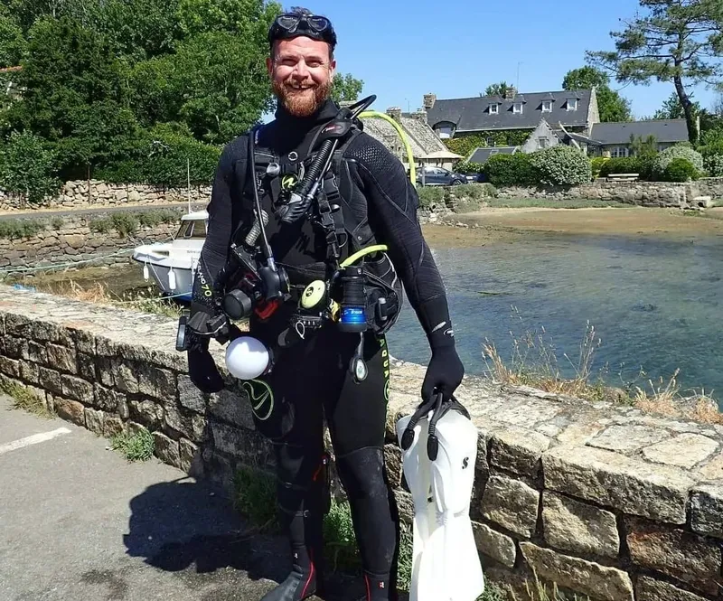 Plongeur équipé sur un quai, prêt pour une immersion en mer