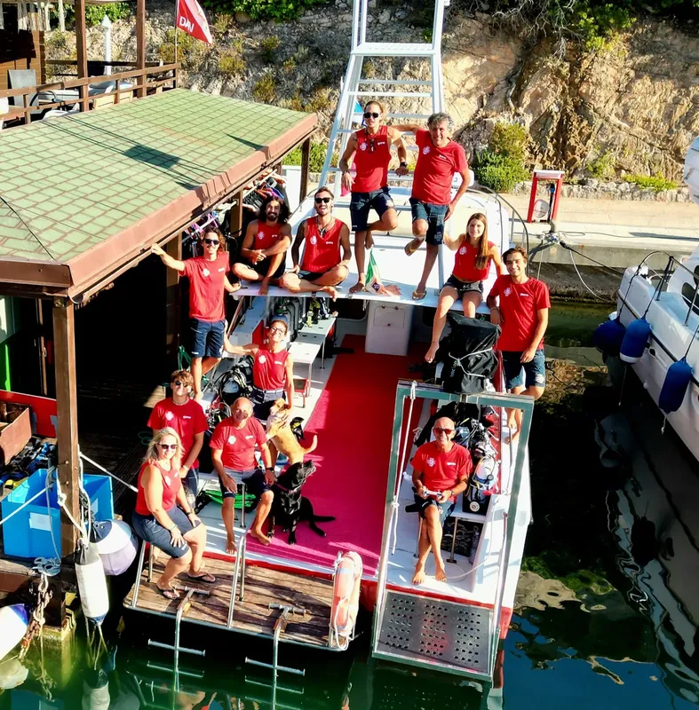 Groupe de plongeurs souriants sur un bateau amarré au ponton