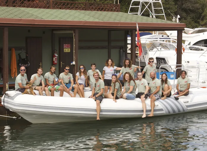 Groupe de personnes souriantes sur un bateau devant un bâtiment