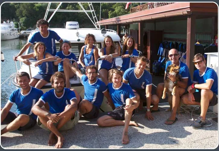 Groupe de personnes souriantes posant sur un bateau de plongée au port