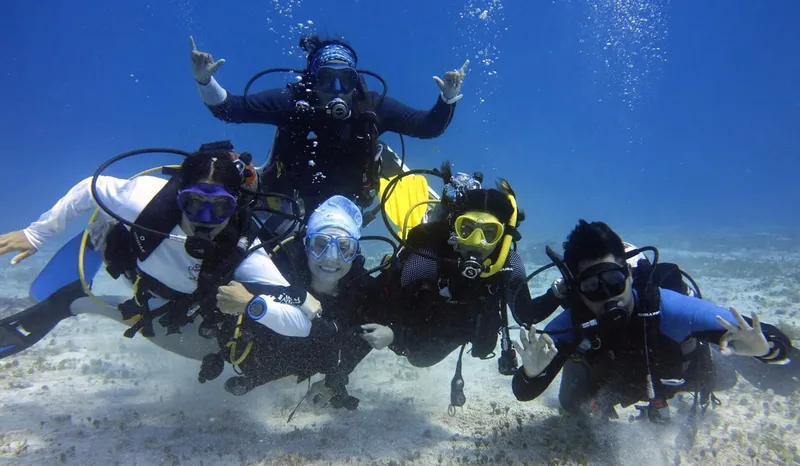 Groupe de plongeurs souriants et faisant des signes de la main sous l'eau