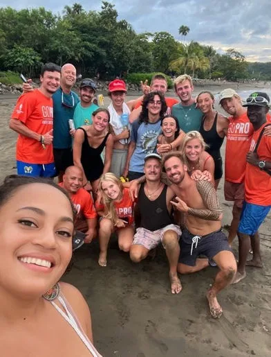 Groupe de personnes souriantes sur une plage de sable gris
