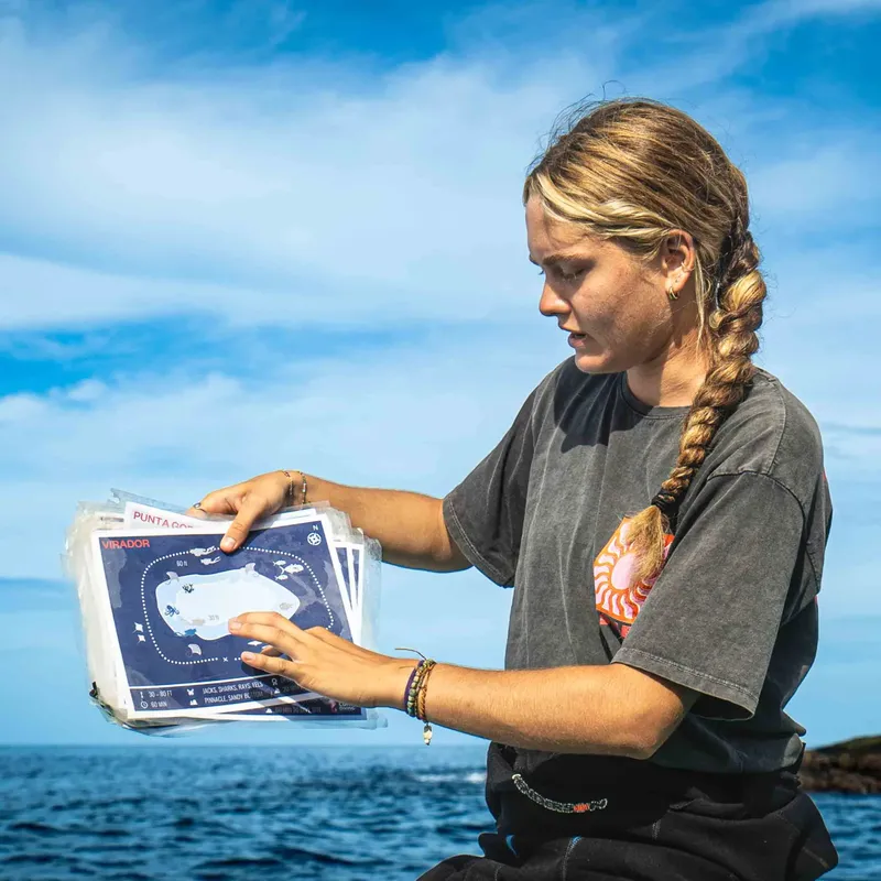 Jeune femme examine une carte marine plastifiée en mer, concentrée