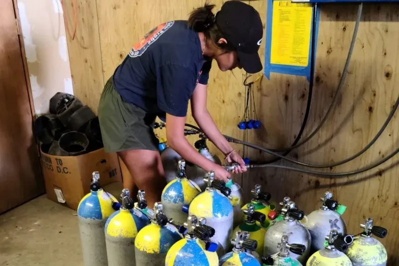 Une personne manipule des bouteilles de plongée dans un local