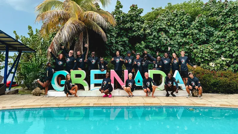 Groupe de personnes souriantes posant devant l'inscription Grenada et une piscine