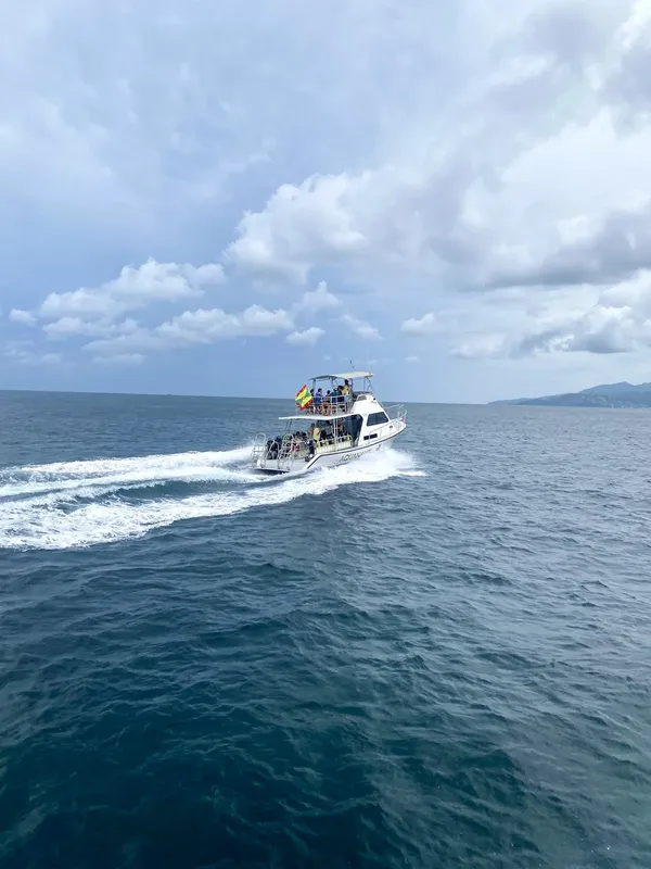 Bateau de plongée navigue sur une mer bleue sous un ciel nuageux