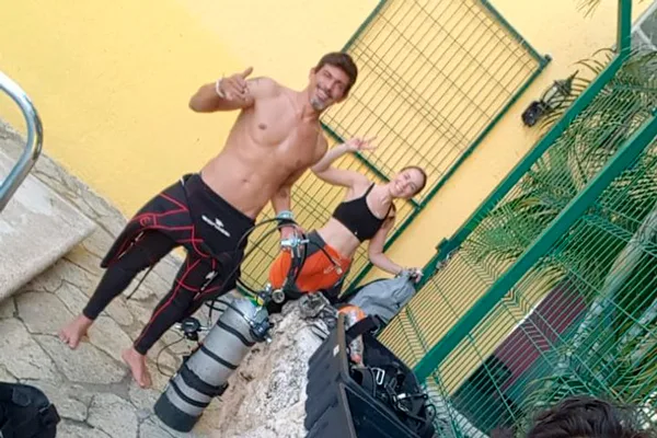 Deux plongeurs souriants avec leur équipement près de bouteilles