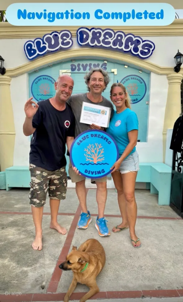 Trois personnes souriantes avec un certificat de plongée et un chien