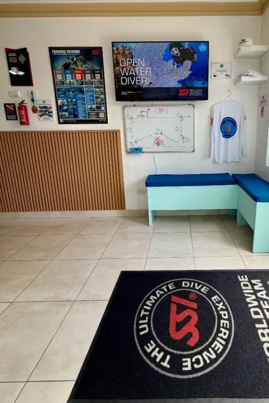 Intérieur d'un centre de plongée avec comptoir, écran et logo au sol