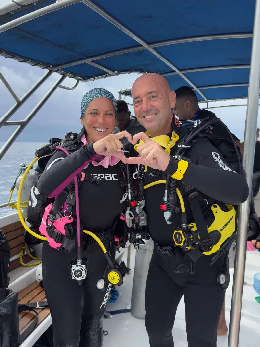 Deux plongeurs souriants en combinaison sur un bateau de plongée