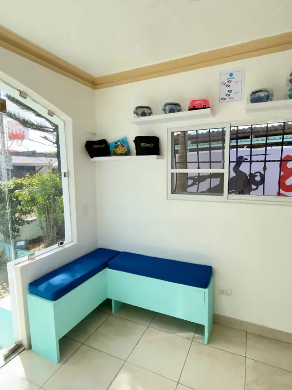 Intérieur lumineux avec banc bleu, fenêtres et quelques accessoires de plongée