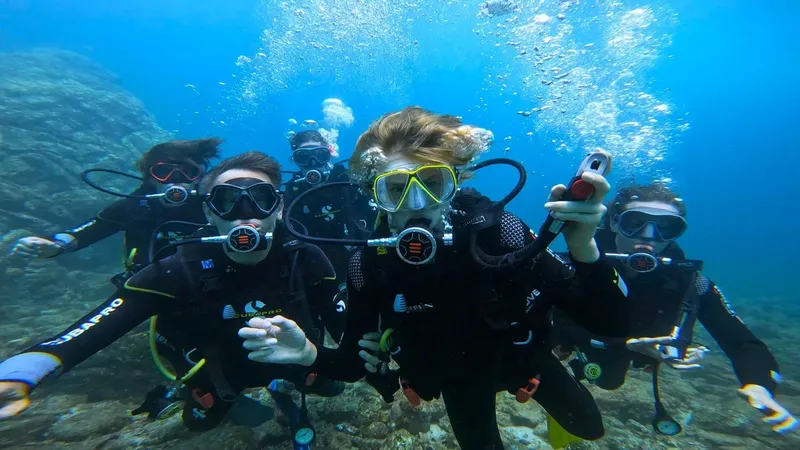Groupe de plongeurs souriants avec équipement complet sous l'eau