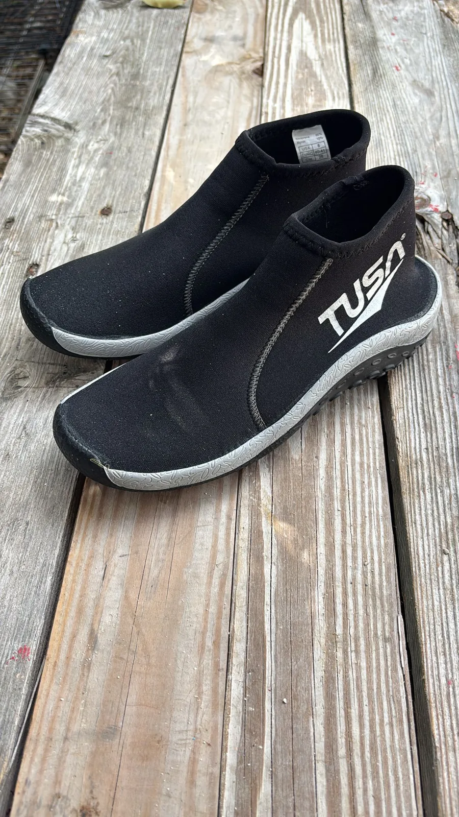 Chaussons de plongée noirs TUSA sur une surface en bois