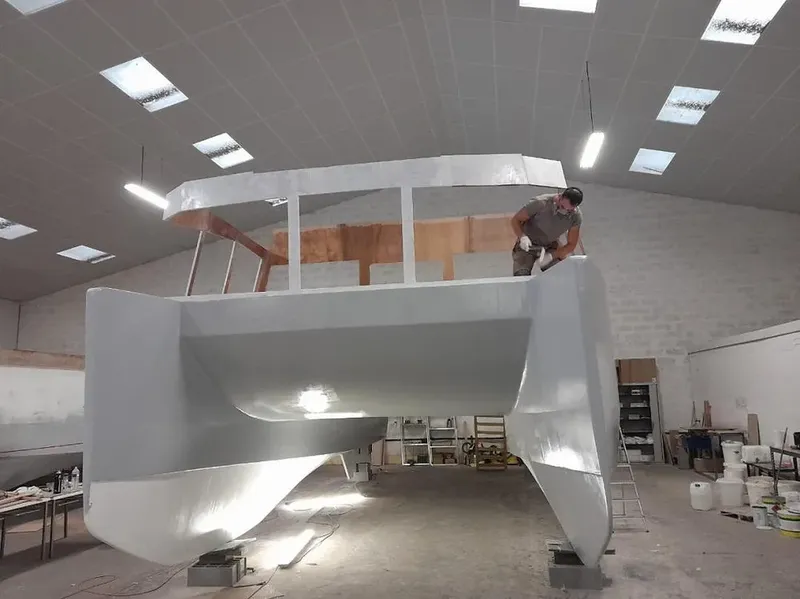 Un homme travaille sur la coque d'un bateau en atelier